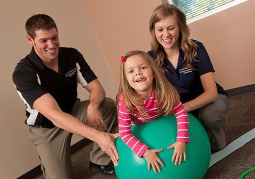 两个ATSU学生和一个儿童病人在健身球上