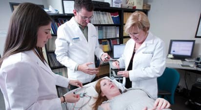 女性ATSU教授展示EMG和ENG女性病人整骨疗法的医学学生观察。
