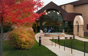 进入ATSU卫生管理学院的入口，前面有一棵树，上面有秋天的叶子。