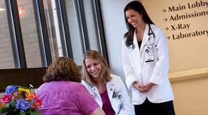 穿着白大褂的女医学生微笑,而与患者咨询。